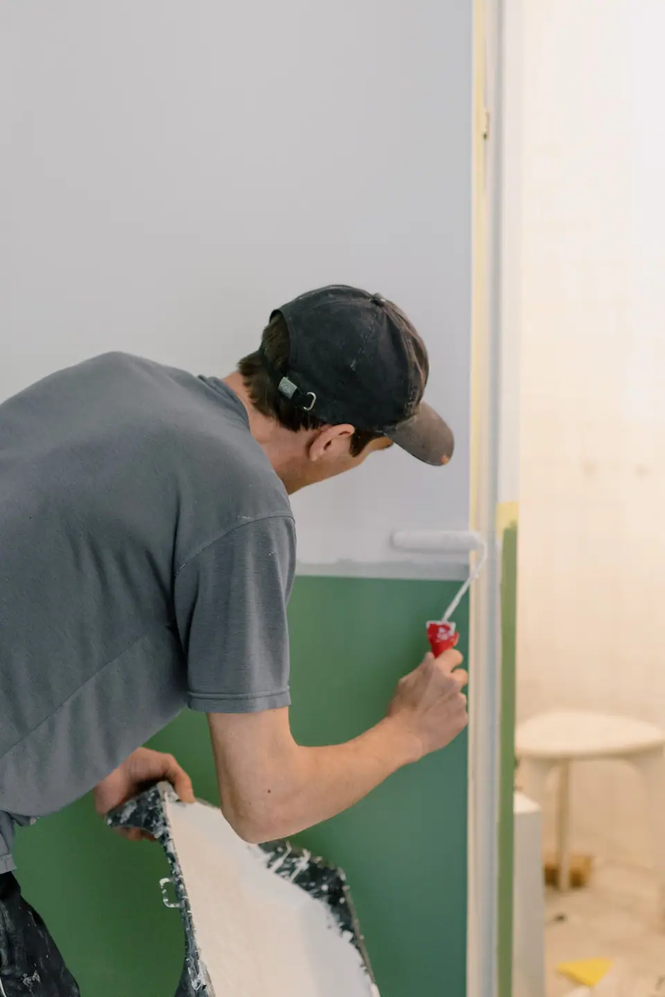 Pintor de costas aplicando tinta com rolo em uma parede interna